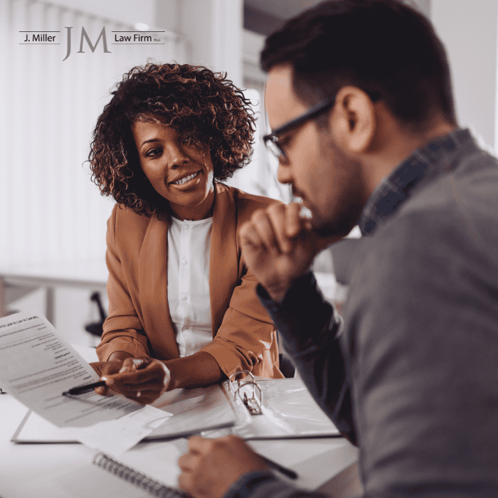 Two colleagues in a modern office review legal documents, with the J. Miller Law Firm logo in the corner.